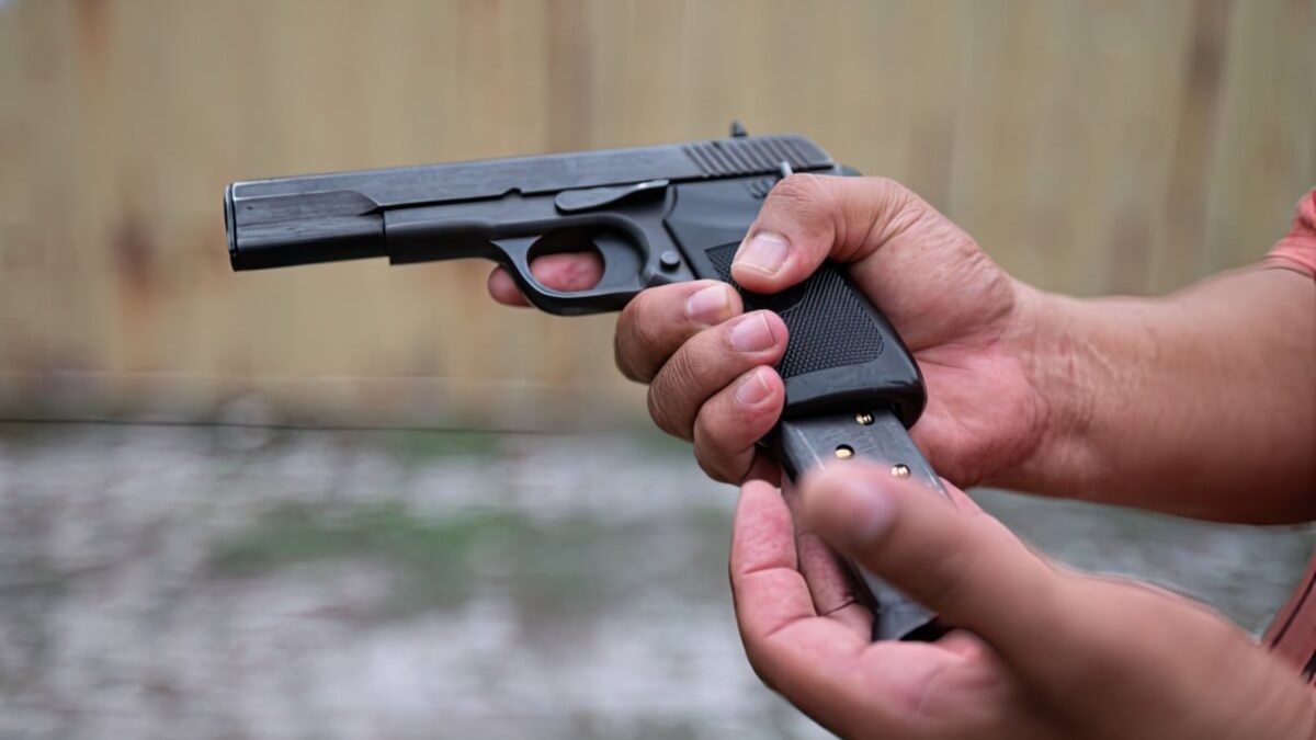 Hands holding a pistol and inserting a magazine