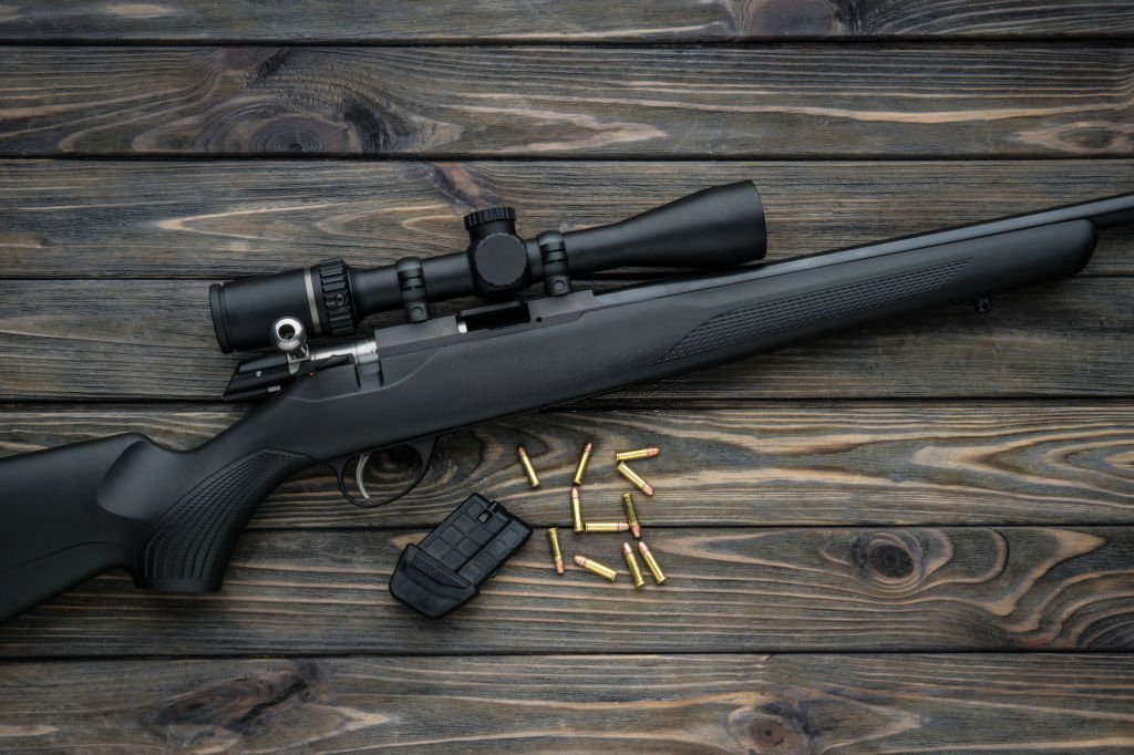 A bolt action rifle with a site on a wooden table close up