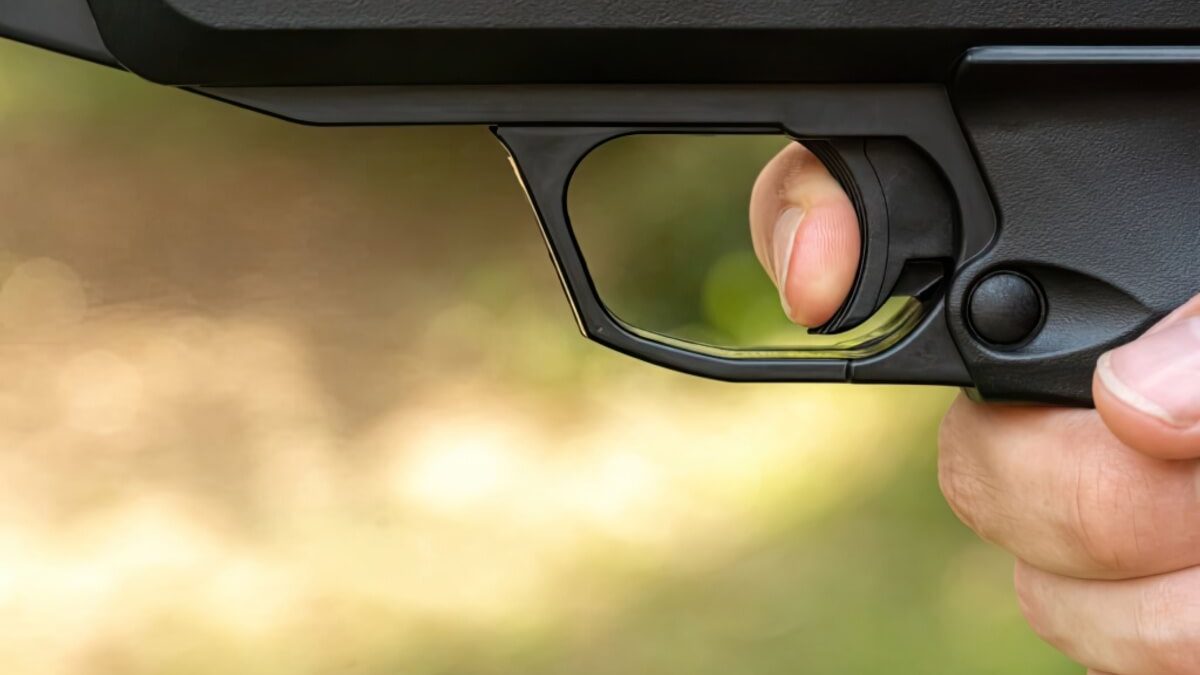 A close up of a trigger with a fi ger pulling it
