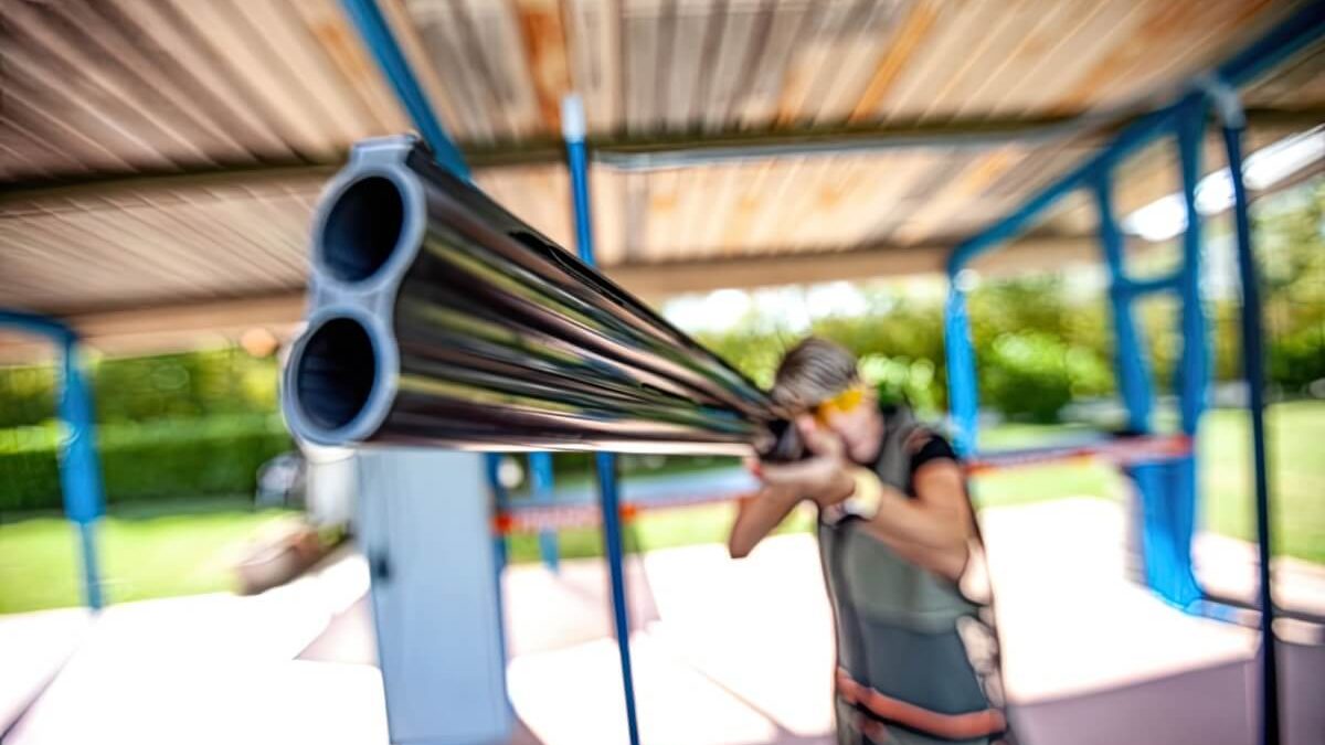 A woman holding a rifle and pointing it towards the camera