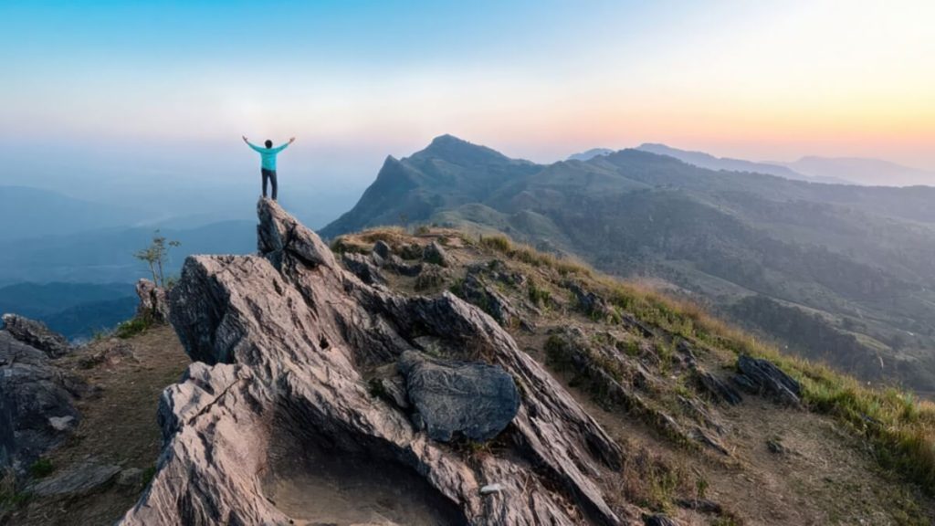A man on a mountain peak with arms up