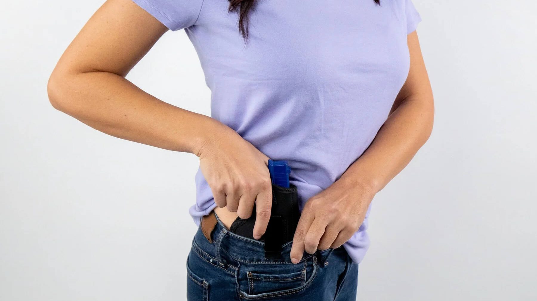 A woman demonstrating the use of an IWB holster