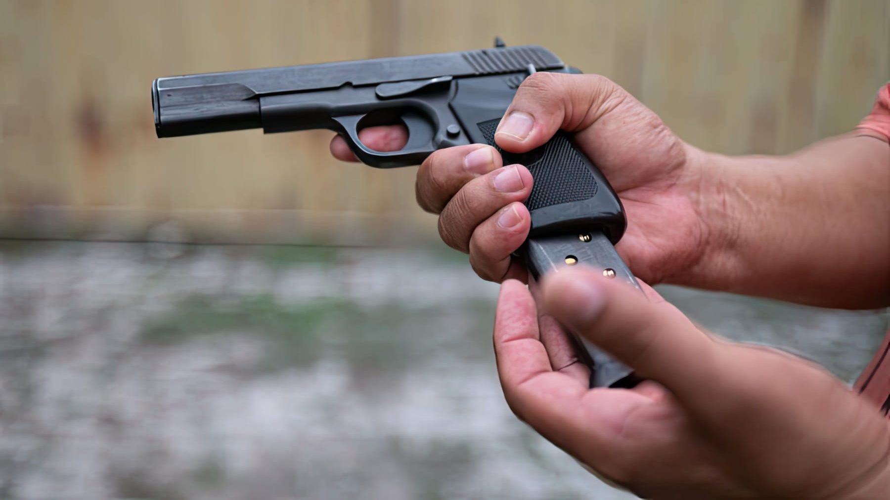 A Man Inserting A Magazine Into A Gun