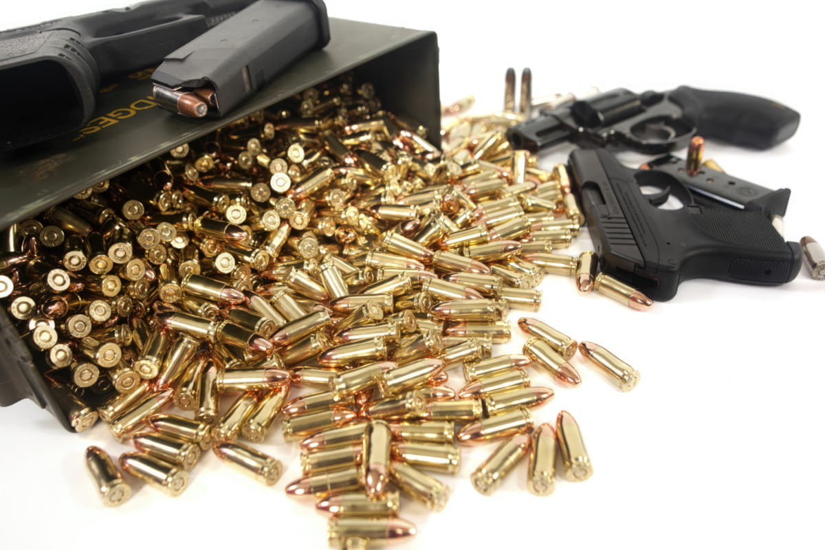 Ammunition Spilling Out Of An Ammo Storage Box Next To Firearms