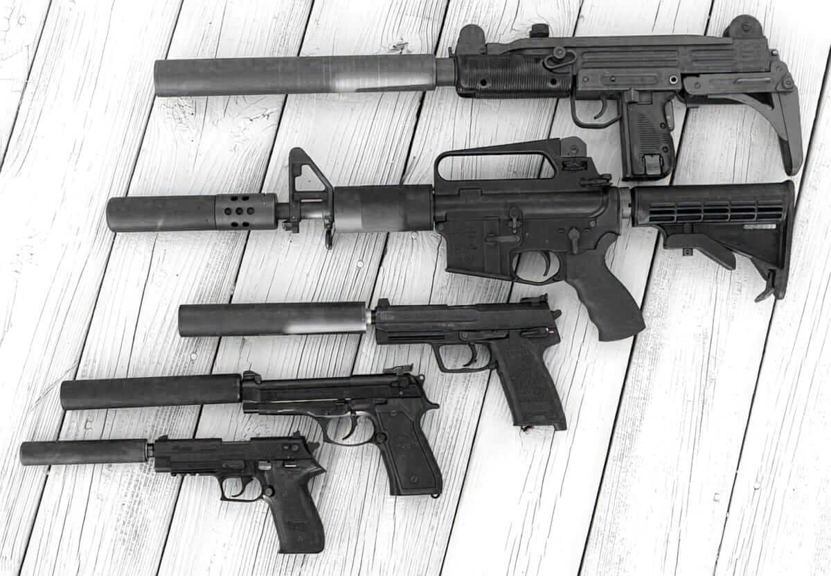 A Selection Of Various Firearms On A White Surface With Silencers Giga